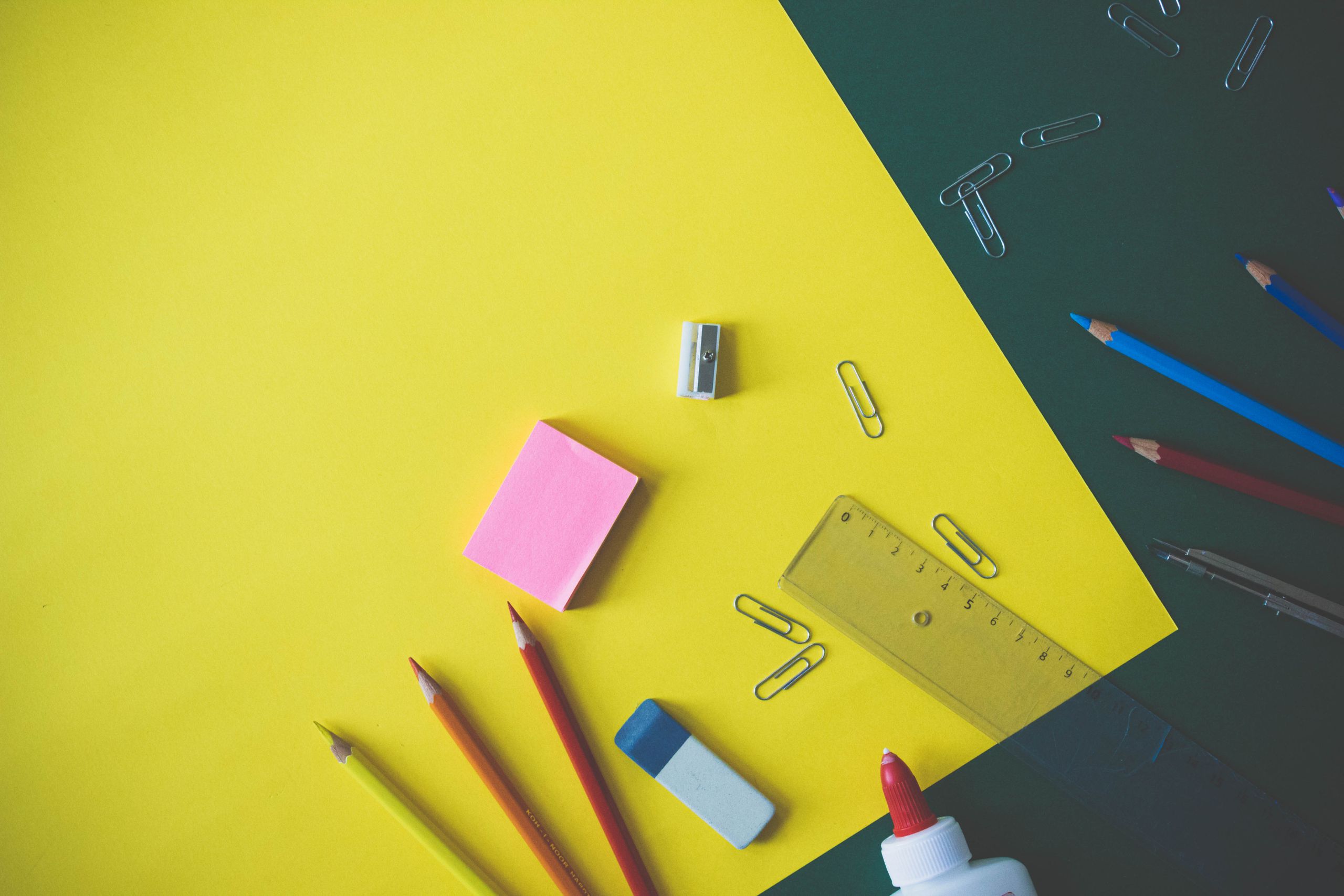 Flat lay of colorful school supplies arranged on a vibrant yellow background, ideal for back-to-school themes.